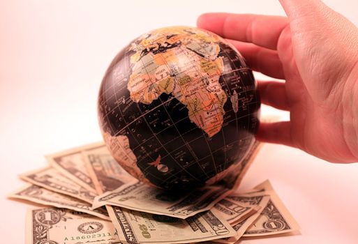 Hand rolling globe over U.S. currency. Abstract image showing finances, global market, investment, economy and market trends.