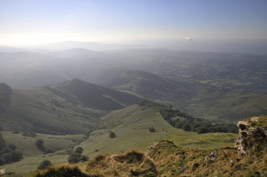 Misty landscape with little mountains and blue sky at the end of afternoon