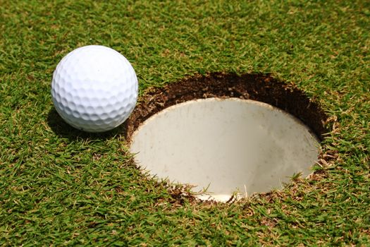 A golf ball on the edge of a hole