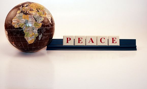 Small globe and peace words isolated on white background. Global friendship and economic growth for the world.