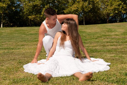 young couple happy sitting on grass white clothes, love relationship