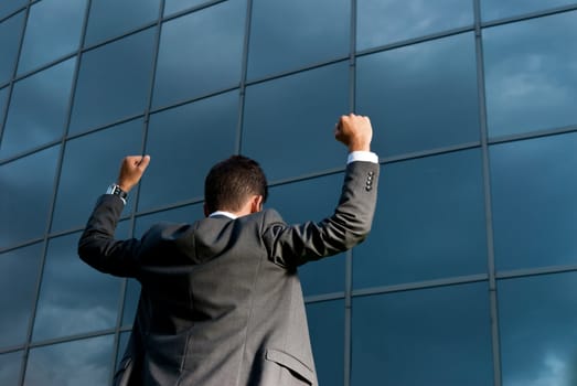 Young successful businessman celebrating a goal on a modern building background