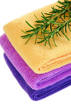 pile of colorful towels with rosemary sprig over white