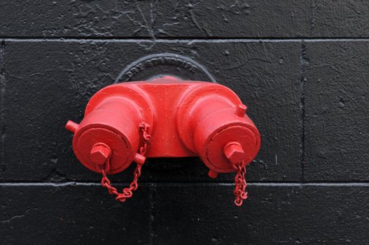 Bright red fire hydrant on a stone wall