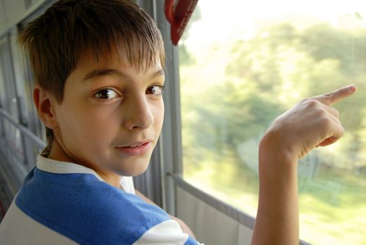 caucasian boy pointing on something by finger through train window