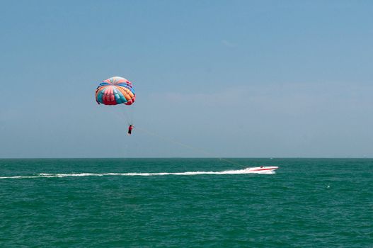 One man is parasailing over the clean sea.