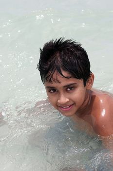 An handsome Indian kid playing in the water