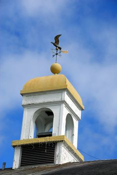 An old wind cock at the top of a modern building