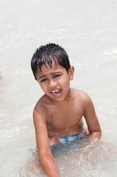An handsome Indian kid playing in the water