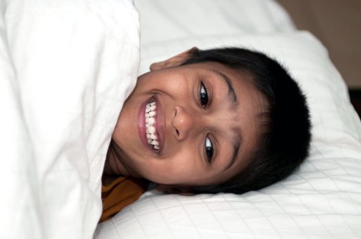 Handsome Indian kid lying happily on the bed