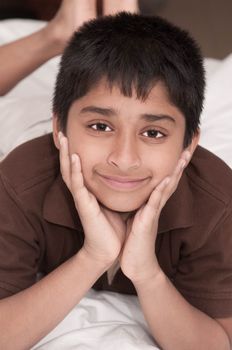 Handsome Indian kid lying happily on the bed