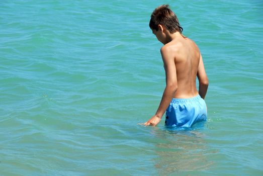 young caucasian boy is going to swim in turquoise water of Red Sea in Egypt