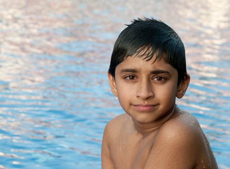 an handsome indian boy swimming happily in the pool