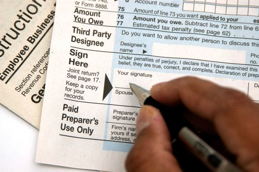 Hand signing a tax form concept of filing tax