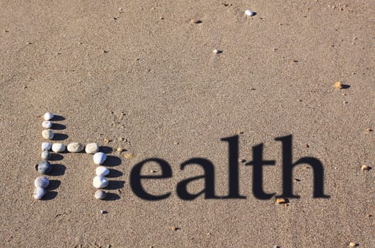 A lower cased letter 'h' formed by beach pebbles on the sand. The word health is spelt out by the addition of shadowed text.