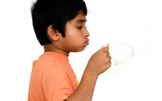 An handsome Indian kid blowing bubbles and having fun