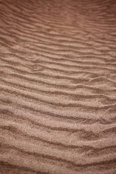 A portrait format image of ripples in the sand made by the outgoing tide.