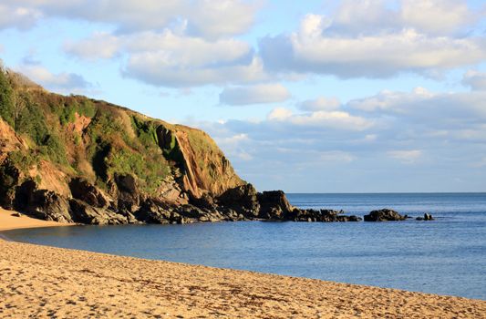 A winter beach scene. Late afternoon sunset over the cove at Blackpool Sands beach, Devon.