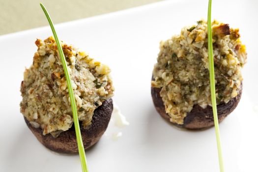 Button mushrooms stuffed with chopped nuts herbs and spices topped with a chive.