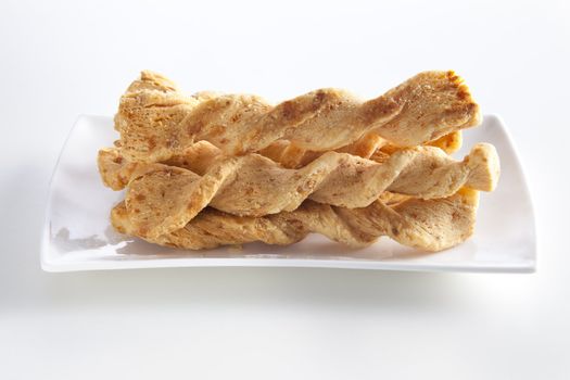 Cheese sticks on white plate with plain background.
