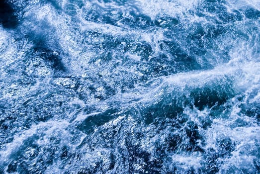 Patterns in a fast moving river at base of waterfall