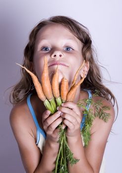 A little girl holding in her hand a beautiful carrots