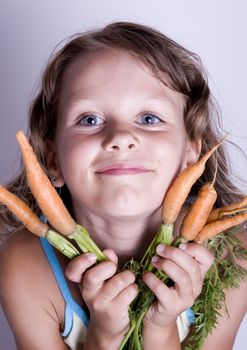 A little girl holding in her hand a beautiful carrots