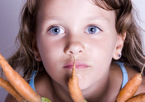 A little girl holding in her hand a beautiful carrots