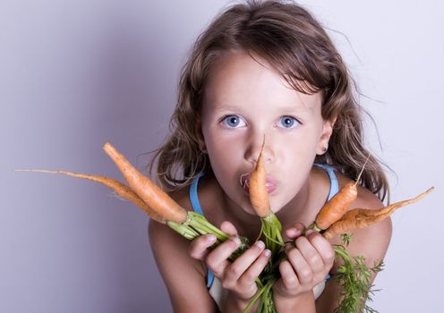 A little girl holding in her hand a beautiful carrots