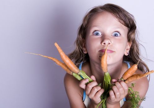 A little girl holding in her hand a beautiful carrots