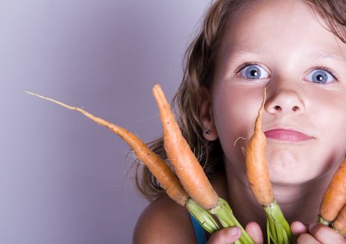 A little girl holding in her hand a beautiful carrots