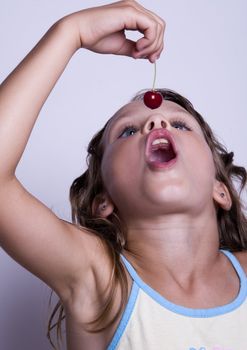 A sweet young girl eating fresh fruit. The child is on a white background