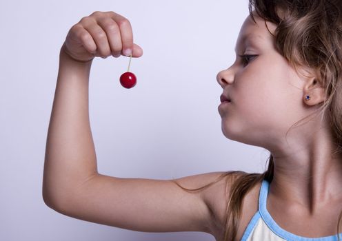 A sweet young girl eating fresh fruit. The child is on a white background