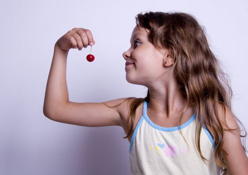 A sweet young girl eating fresh fruit. The child is on a white background