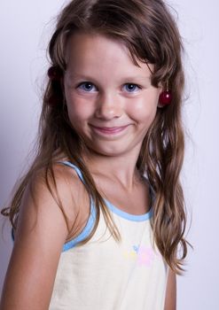 A sweet young girl eating fresh fruit. The child is on a white background