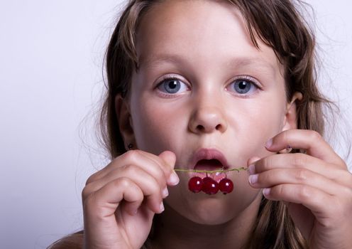 A sweet young girl eating fresh fruit. The child is on a white background