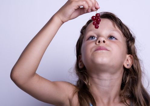 A sweet young girl eating fresh fruit. The child is on a white background