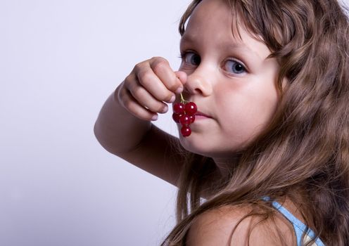 A sweet young girl eating fresh fruit. The child is on a white background