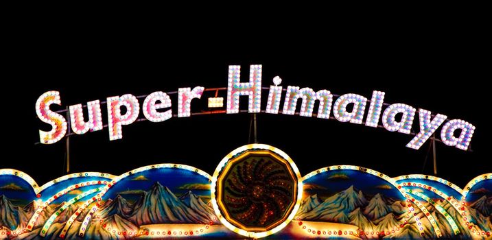 A lit up Super Himalaya sign above a ride at an amusement park