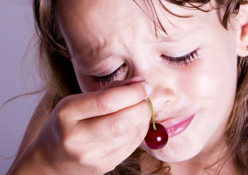 A sweet young girl eating fresh fruit. The child is on a white background