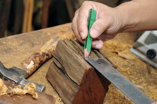 Close-up of a carpenter taking a measurement of a wood.