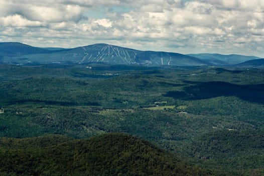 View of mountains and ski slopes on a summer day. View is from the top of a high mountain in the Green Mountains of Vermont.