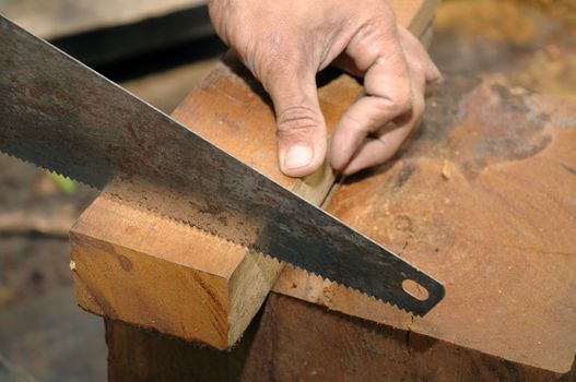 Closeup of a carpenter sawing a wood.