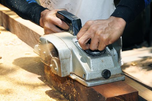 Closeup of a carpenter working with a power belt wood sander.