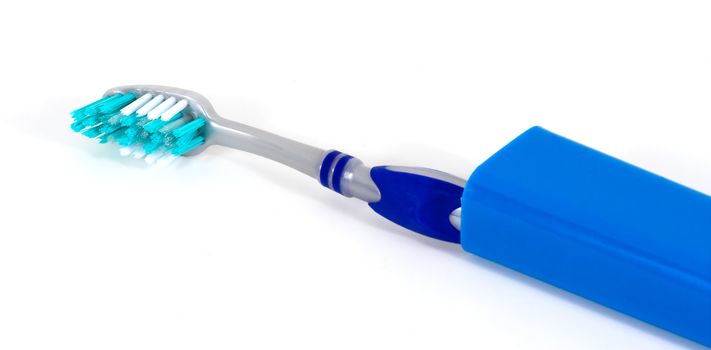 A travel toothbrush with a blue case isolated over white
