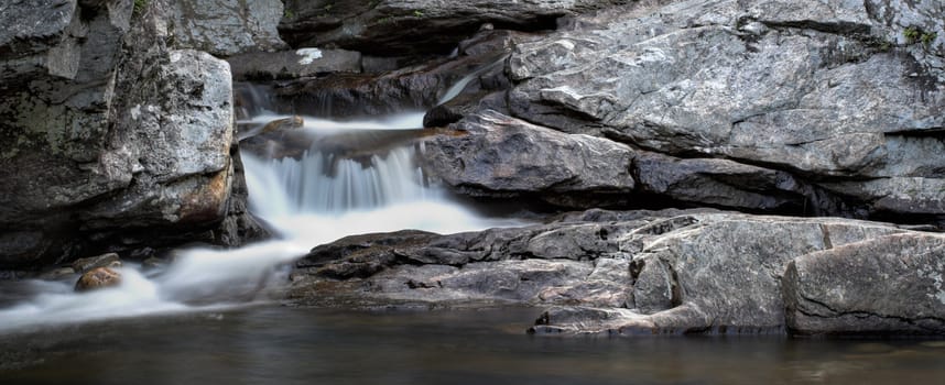 A small waterfall over rock in panorama format