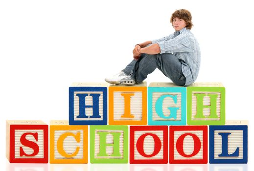 Teen boy sitting on the word high school in giant alphabet blocks.