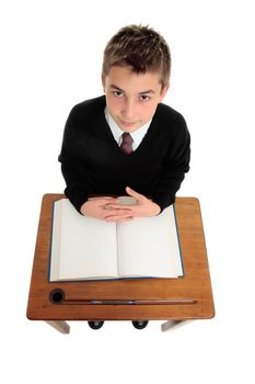 School boy sitting down at a school desk with open book.  White background.
