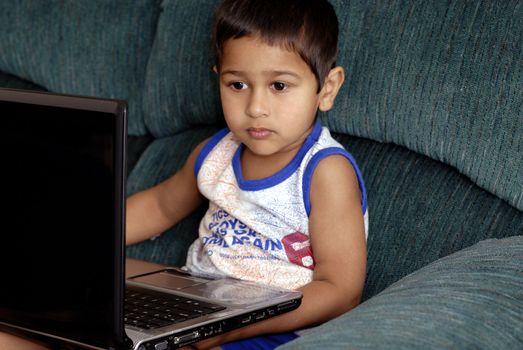 Handsome Indian kid learning using his laptop