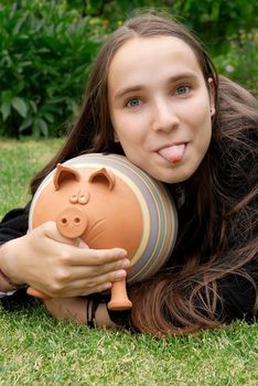Girl sticking her tongue out with piggy bank in her hands